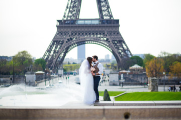 Bride and groom having a romantic moment on their wedding day in Paris, in front of the Eiffel tour