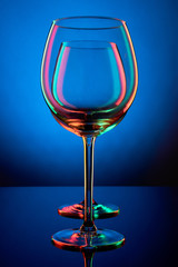 Empty wine glasses in colored red-grin light on a blue background