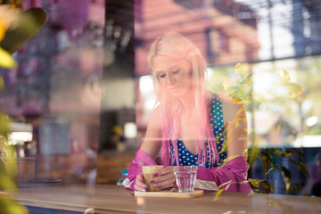 Young beautiful blonde woman drinking coffee at the coffee shop
