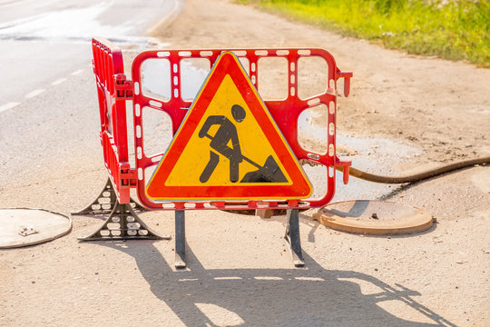 Triangular red and yellow sign road works near hatches.