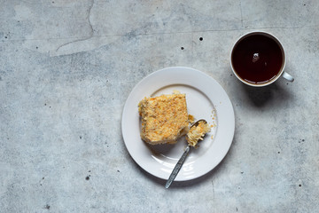 Homemade mille-feuille, puff pastry custard cream pie on white plate, cup of tea on gray background