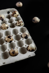Paper tray of farm quail eggs on black background. Eggs located with social distance.