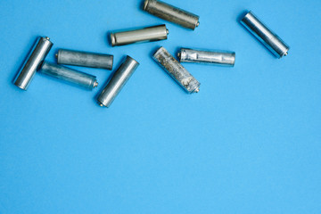 Scattered old dirty batteries aa or aaa size on blue background. Recycling concept. Save environment. Alternative energy