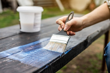 Wood carpenter applies a protective layer of transparent varnish. Hand with a brush close up on the table top