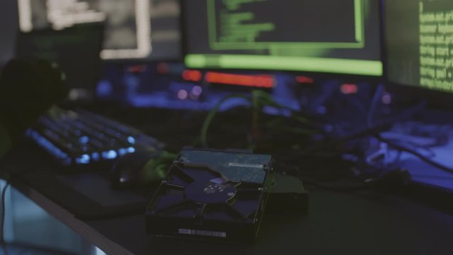 Close up of hands of unrecognizable programmer typing on keyboard and then taking hard disk and starting analyzing it