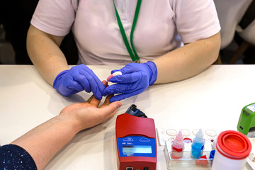 The doctor takes a blood test from the patient 's finger.