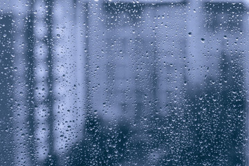 Naklejka na ściany i meble rainy droplets on a blue window glass transparent surface. drops on window shield in a rainy days in night city. stormy weather. isolation sad depression concept. rainy season.
