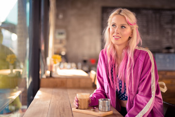 Happy young beautiful blonde woman thinking at the coffee shop