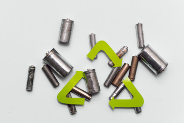 Used batteries with recycling sign top view. Symbol of caring for the environment. Danger of contamination by decomposition products of batteries.