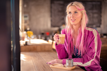 Happy young beautiful blonde woman thinking and relaxing at the coffee shop