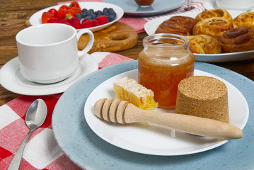 breakfast in the village fresh rolls, coffee, berries and honey laid out on an old brown wooden table.