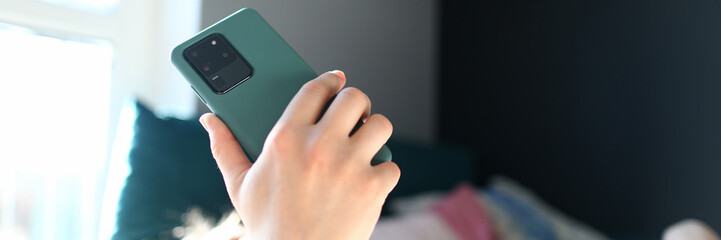 Woman lying bed and looking at smartphone screen