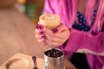 Hands of young woman drinking coffee and relaxing at the coffee shop
