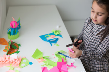 Beautiful little girl cutting paper with scissors on the art lesson class. Children education concept. Kids crafts.Back to schoo