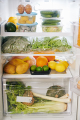 Opened fridge full of groceries like fruits, vegetables, greens and eggs, healthy eating concept