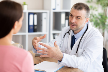 Obraz premium Male experienced doctor talking with his female patient