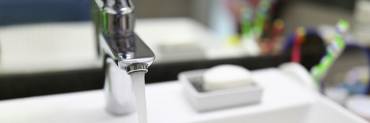 Stream water flows from faucet into bathroom sink