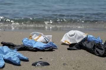 Protective virus mask and plastic gloves garbage trash on sandy sea shore,coronavirus covid pollution disease 