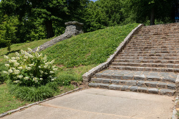 Rough granite block stairs and retaining wall on a hillside, urban park landscape, horizontal aspect