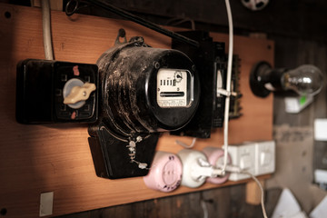 Old electric meter for calculating energy consumption is hanging in the barn, next to sockets and a...