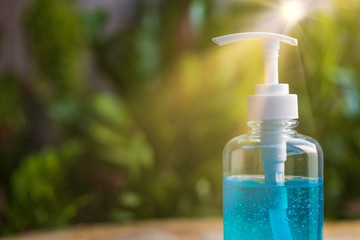 Close up pump of Blue alcohols gel bottle on blur green nature background and sun ray.Hand sanitizer gel in pump bottle. With copy space for text or design.