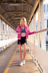 Young beautiful blonde woman at footbridge in the city