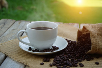 Hot Coffee cup and coffee beans roating on the wooden table