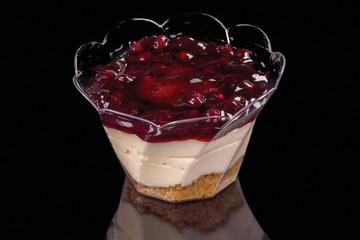 Tasty cheesecake with blueberries cheese in a glass with reflection, isolated on black background.