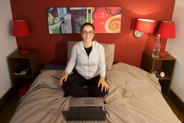 Fototapeta premium ragazza seduta nel suo letto di casa sorride felice