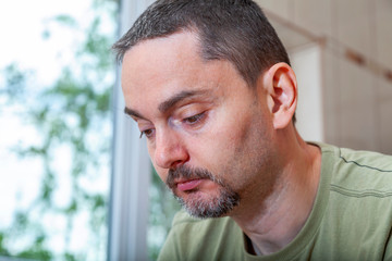 Sad young man looking down. Interior image.