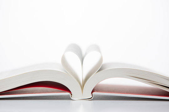 A book seen up close with open pages in the shape of a heart