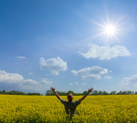 happy man stay among yellow rape field under a sparkle sun, agricultural rural scene