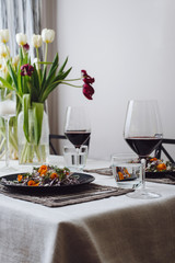 Photo of a home cozy supper with glass of red wine and salad from fresh eco vegetables on black plate indoors