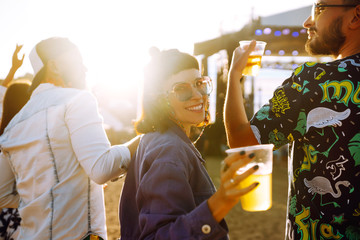 Young happy friends drinking beer and having fun at music festival together. Beach party, summer holiday, vacation concept. Friendship and celebration concept.