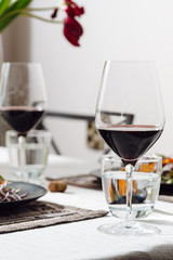 Photo of a home cozy supper with glass of red wine and salad from fresh eco vegetables on black plate indoors