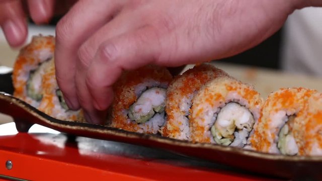 Hands putting sushi. Master sushi rolls puts sushi.