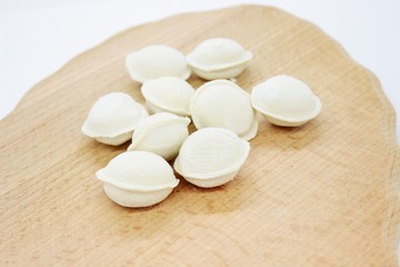 Raw cooked dumplings are located on a wooden surface
