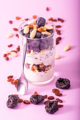 Greek natur yogurt with blueberries, muesli and seeds, photographed in studio on a purple background.
