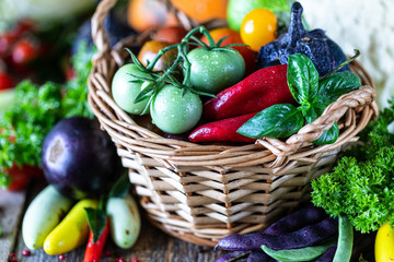 Autumn harvest of vegetables in a wicker basket: tomatoes, beans, squash, pumpkin, cabbage, greens, parsley.