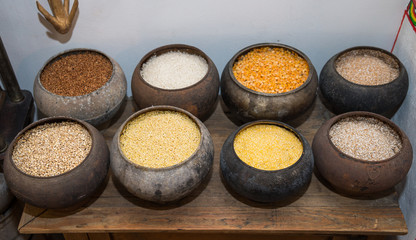 Eight different cereals for porridge in old cast-iron kettles on wooden table