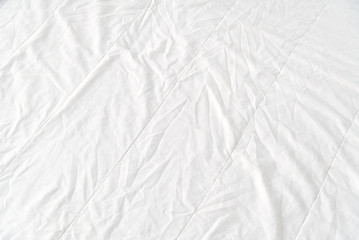 Fototapeta na wymiar Top view of wrinkles on an unmade bed sheet after waking up in the morning. Bed Cleaning, Fresh bed concept