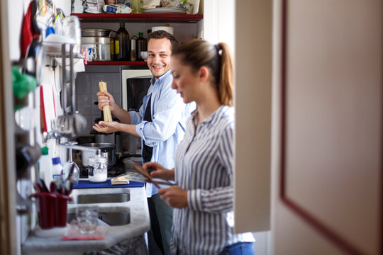 Coppia di fidanzati scherza e ride divertita mentre prepara il pranzo in cucina