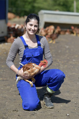 Smiling young farmer holding hen