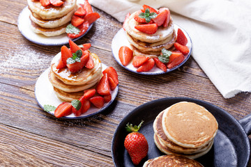 Obraz na płótnie Canvas Pancakes with fresh strawberries on wooden table