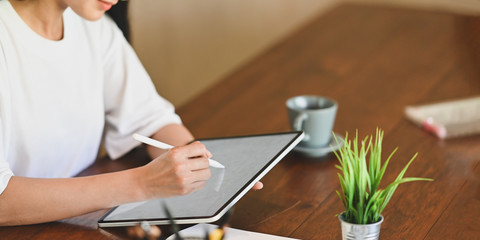 Cropped image of quiet woman drawing on white blank screen computer laptop with stylus pen while...