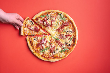 Woman grabbing a slice of pizza. Pizza ham top view