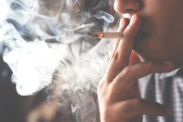 asian man smoking a cigarette smoke spread dark background. concept campaign No smoking and health...