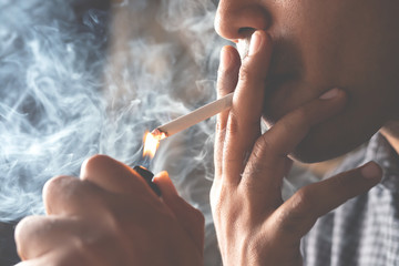 asian man handle use lighters burn cigarette smoke spread dark background. concept campaign No...
