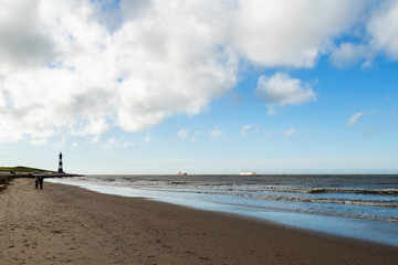 Scenery at the seaside with lighthouse and passing ships in Breskens, Netherlands
