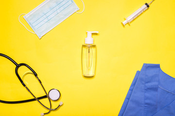hands dispenser surrounded by medical items on a yellow background
